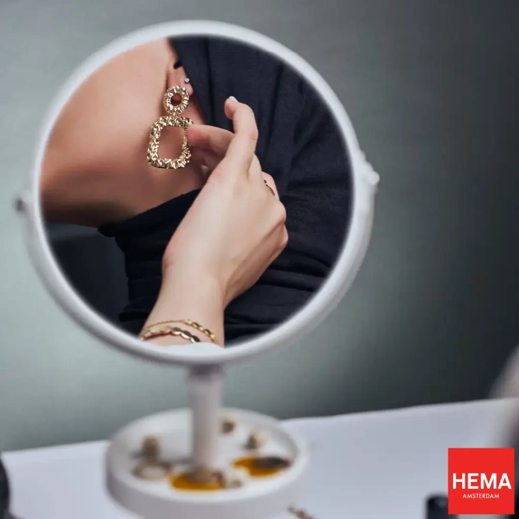 امرأة تنظر في مرآتها مرتديها أقراطها من هايما